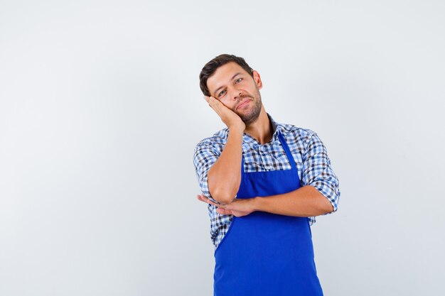 Jovem cozinheiro com um avental azul e uma camisa