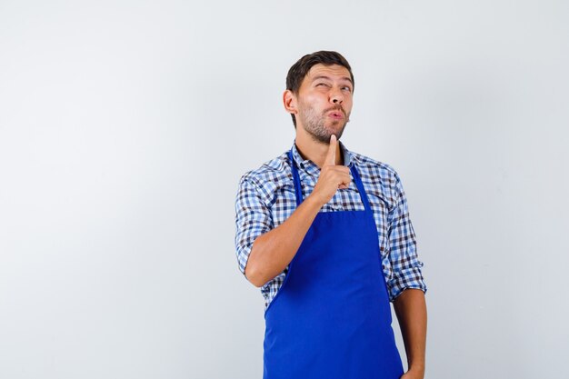 Jovem cozinheiro com um avental azul e uma camisa