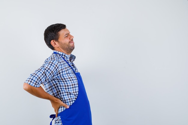 Jovem cozinheiro com um avental azul e uma camisa