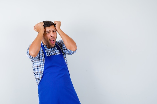 Jovem cozinheiro com um avental azul e uma camisa