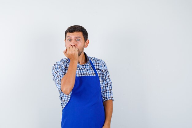 Jovem cozinheiro com um avental azul e uma camisa