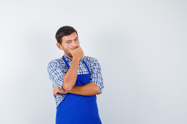 Jovem cozinheiro com um avental azul e uma camisa