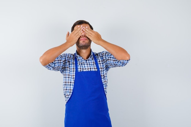 Jovem cozinheiro com um avental azul e uma camisa