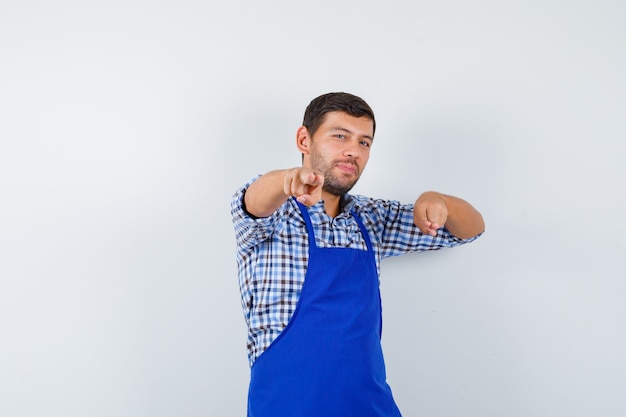 Foto grátis jovem cozinheiro com um avental azul e uma camisa