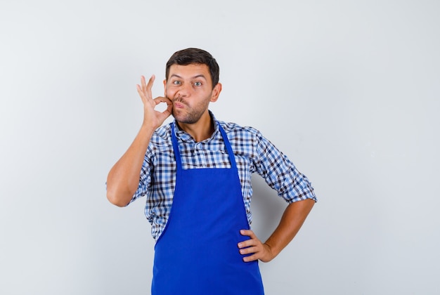 Jovem cozinheiro com um avental azul e uma camisa