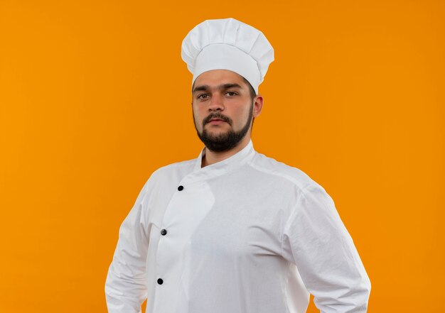 Jovem cozinheiro com uniforme de chef em pé e olhando