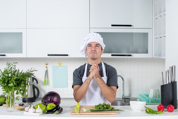 Jovem cozinheiro satisfeito com uniforme de mãos dadas