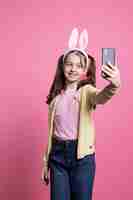 Foto grátis jovem criança animada a tirar fotografias com o telemóvel na câmara