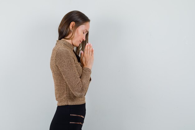 Jovem de blusa dourada orando e parecendo esperançosa. espaço livre para o seu texto