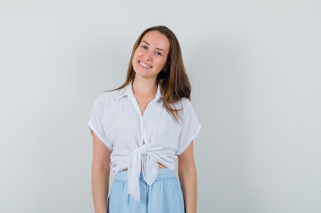 Jovem de blusa, saia sorrindo enquanto fica na frente da frente e parece fofa