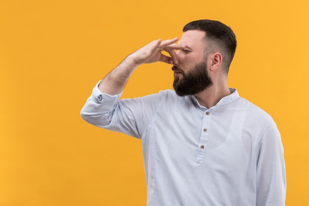 Foto grátis jovem de camisa branca com barba, cobrindo o nariz devido ao cheiro