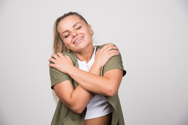 Jovem de camisa branca se abraça.