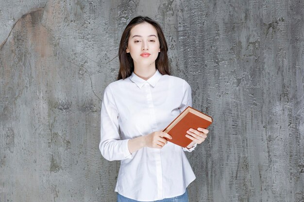 Jovem de camisa branca segurando o livro para sua classe. foto de alta qualidade