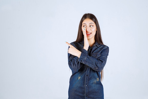 Jovem de camisa jeans sussurrando e fofocando