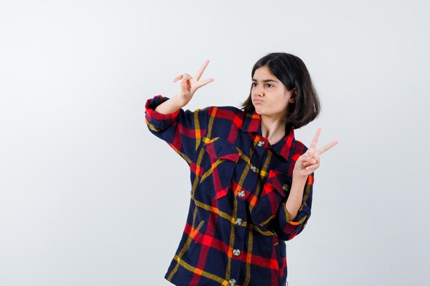 Foto grátis jovem de camisa quadrada, mostrando gestos de paz e olhando bonita, vista frontal.