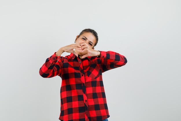 Foto grátis jovem de camisa quadrada, mostrando o gesto do coração, vista frontal.