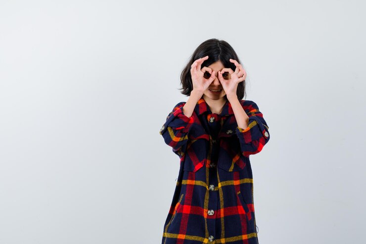 Foto grátis jovem de camisa quadrada, mostrando sinais de ok nos olhos e olhando fofa, vista frontal.