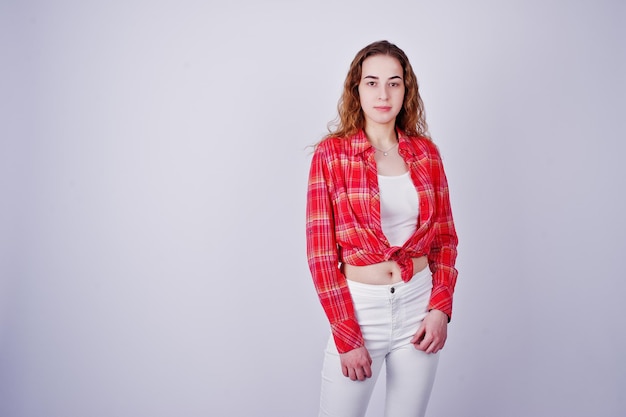 Jovem de camisa vermelha e calça branca contra fundo branco no estúdio