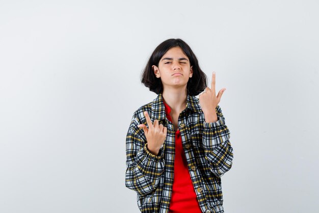 Jovem de camisa xadrez e camiseta vermelha apontando para cima e olhando bonita, vista frontal.