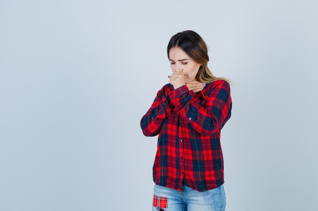 Foto grátis jovem de camisa xadrez, jeans, sofrendo de tosse e parecendo doente, vista frontal.