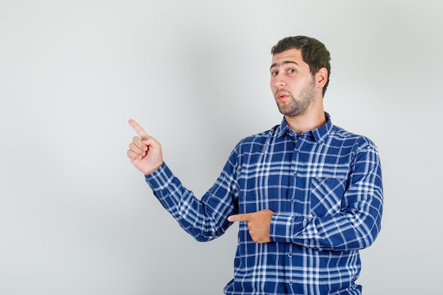 Foto grátis jovem de camisa xadrez mostrando algo com os dedos