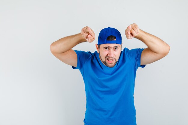 Jovem de camiseta azul e boné apontando para a frente e olhando seguro