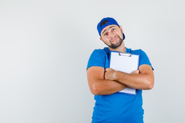 Jovem de camiseta azul e boné segurando a prancheta com força e parecendo tranquilo