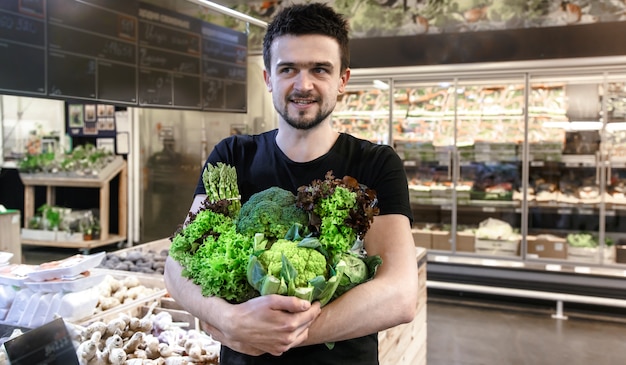 Foto grátis jovem de camiseta preta comprando apenas vegetais verdes no mercado