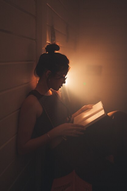 Jovem de óculos lendo um livro em uma aconchegante sala de estar