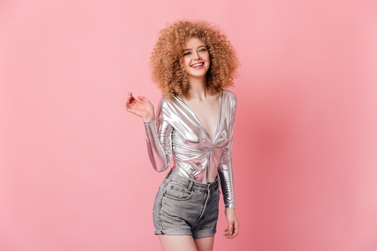 Foto grátis jovem de ótimo humor, posando no espaço rosa. retrato de loira encaracolada em top prata e shorts.