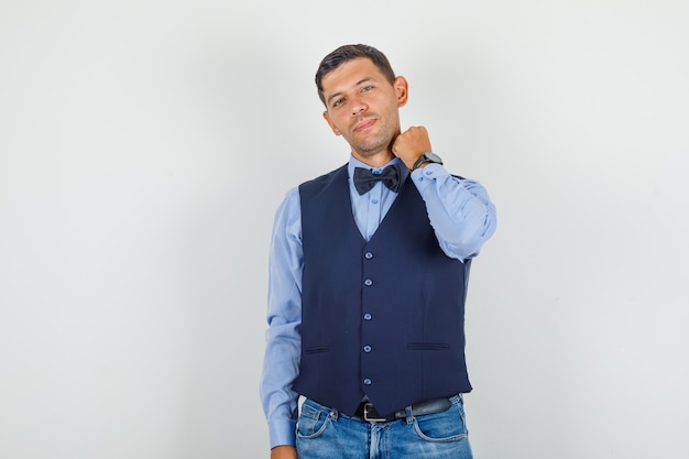 Jovem de terno, jeans posando com a mão segurando o colarinho e parecendo elegante