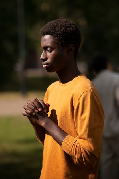 Jovem de tiro médio rezando ao ar livre