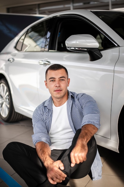 Foto grátis jovem de vista frontal em uma concessionária de carros