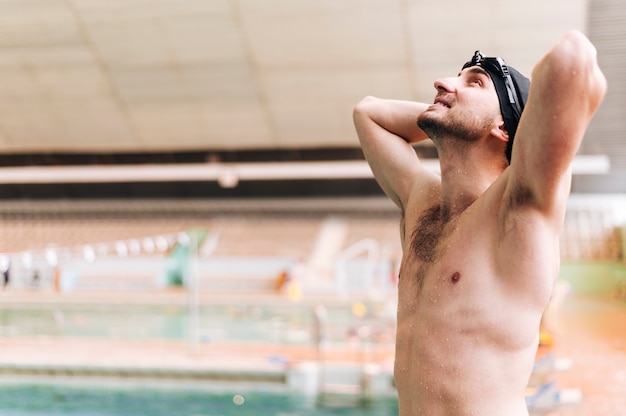 Jovem de vista lateral na piscina, olhando para cima