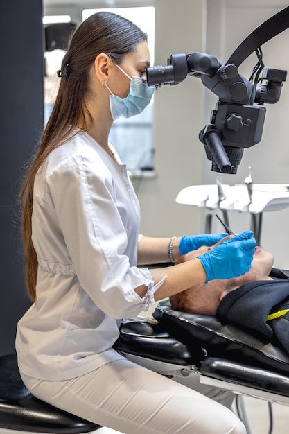 Jovem dentista tratando dentes de pacientes com microscópio dental conceito de odontologia