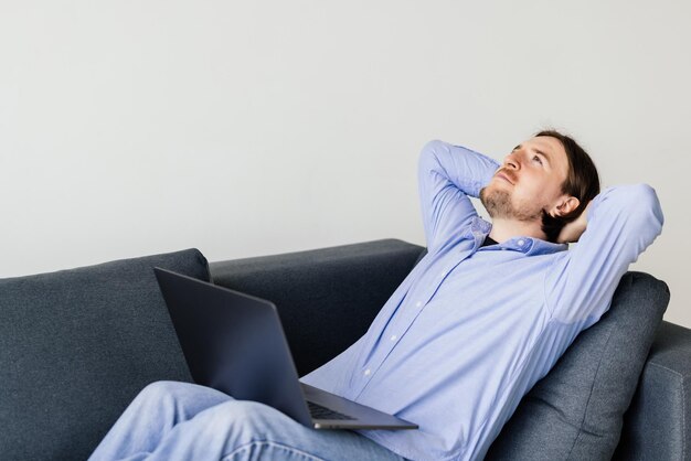 Jovem descansando em um sofá com um laptop