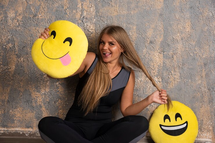 Foto grátis jovem desportiva em trajes de esporte, segurando um sorriso e língua para fora emoji travesseiros e se divertindo.