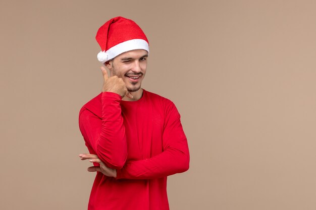 Jovem do sexo masculino com expressão sorridente em fundo marrom e emoção de férias de Natal