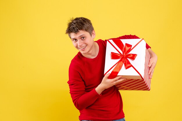 Jovem do sexo masculino com grande Natal presente em fundo amarelo