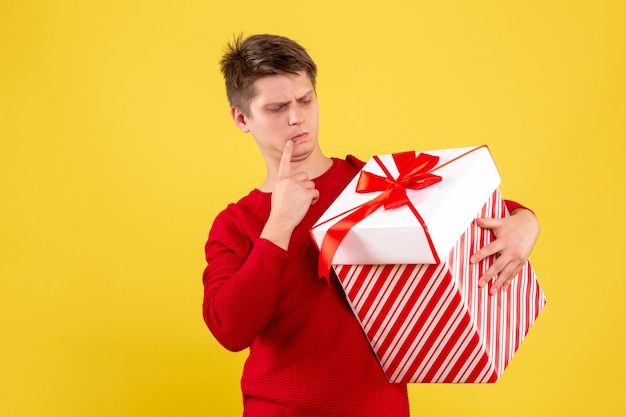 Jovem do sexo masculino com grande Natal presente em fundo amarelo