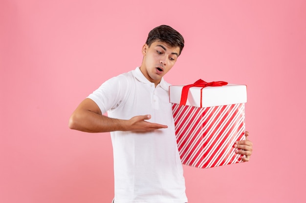 Jovem do sexo masculino com grande presente de Natal em fundo rosa claro