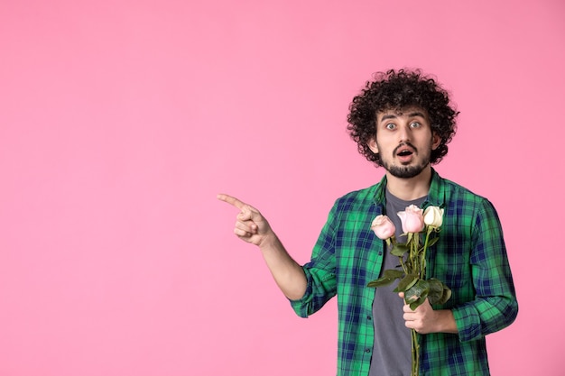 Foto grátis jovem do sexo masculino com rosas cor de rosa na frente