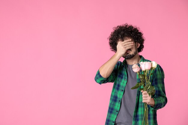 Jovem do sexo masculino com rosas cor de rosa na frente