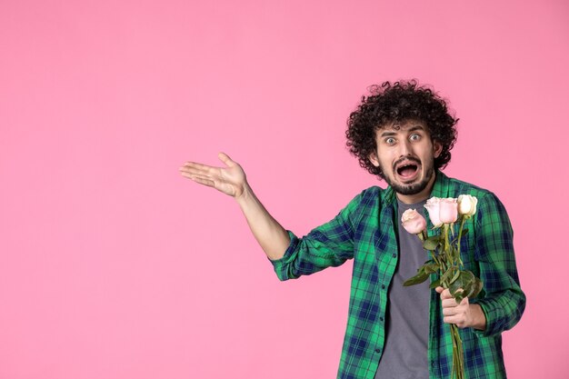 Jovem do sexo masculino com rosas cor de rosa na frente