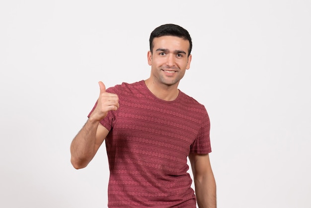 Jovem do sexo masculino com uma camiseta vermelho-escura em pé sobre um fundo branco de frente