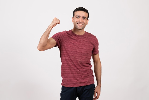 Jovem do sexo masculino com uma camiseta vermelho-escura em pé sobre um fundo branco de frente