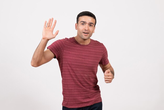 Jovem do sexo masculino com uma camiseta vermelho-escura em pé sobre um fundo branco de frente