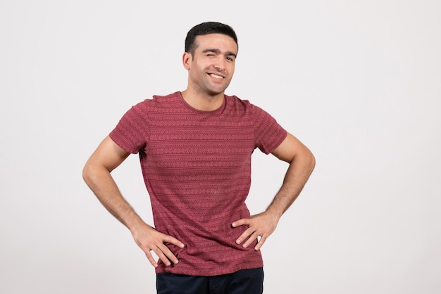 Jovem do sexo masculino com uma camiseta vermelho-escura em pé sobre um fundo branco de frente