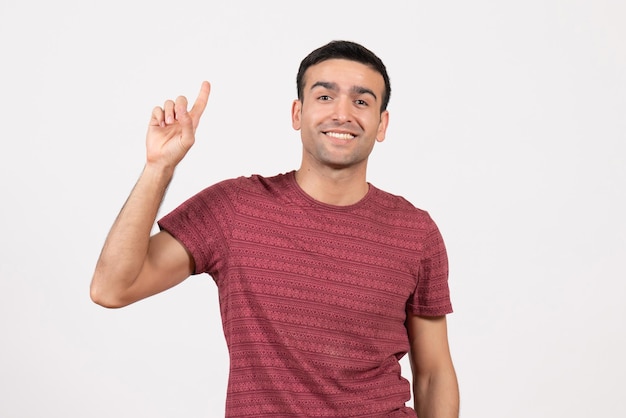 Jovem do sexo masculino com uma camiseta vermelho-escura em pé sobre um fundo branco de frente