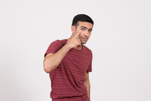 Jovem do sexo masculino com uma camiseta vermelho-escura em pé sobre um fundo branco de frente